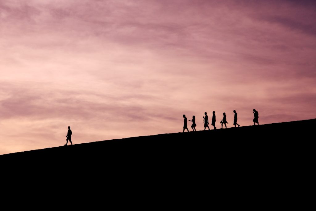 person walking down a hill ahead of a line of people